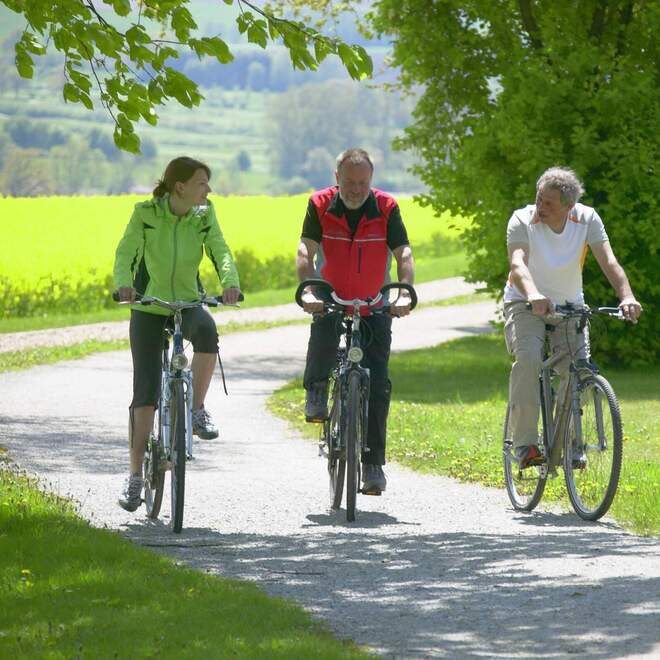 zwei Joggende Personen im Grünen - im Hintergrund der Anschein an Wasser.