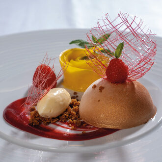 Lächelnde Frau im Grünen, die sitzend nach vorn gebeugt ist.