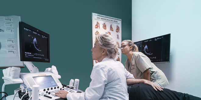 Eine Ärztin führt eine Ultraschalluntersuchung an einem auf der Seite liegenden Patienten durch. Kardiologische Untersuchung in der Asklepios Klinik durch Frau Dr. med. Petra Heizmann