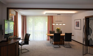 Ein Esstisch und ein Fernseher in einem Hotelzimmer am Wolfgangsee Ein Wohnraum in einem großen Hotelzimmer