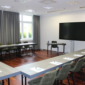 Ein stilvoll eingerichteter Konferenzraum mit mehreren Tischen und Stühlen eignet sich gut für Tagungen Tagungen und andere Veranstaltungen können Sie bei uns in den Räumlichkeiten des Hotels St. Wolfgang ideal durchführen